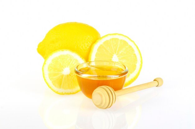 Lemon juice and honey mask mixture in a bowl, with fresh lemon slices and a honey jar nearby.